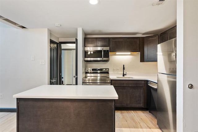 1052 S Kingshighway Blvd, Saint Louis, MO 63110 - kitchen featuring appliances with stainless steel finishes, a sink, dark brown cabinets, and light wood finished floors