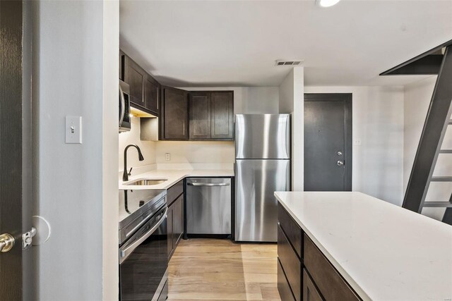 1052 S Kingshighway Blvd, Saint Louis, MO 63110 - kitchen featuring stainless steel appliances, a sink, dark brown cabinets, light wood-style flooring, and light countertops
