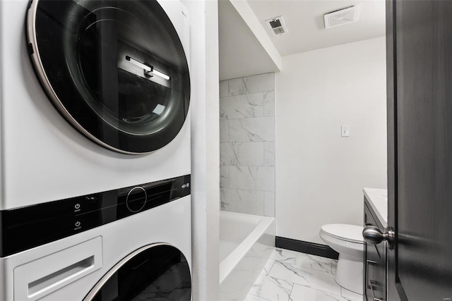 1052 S Kingshighway Blvd, Saint Louis, MO 63110 - full bath with marble finish flooring, stacked washer / drying machine, baseboards, toilet, and vanity