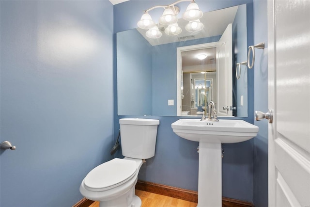 1052 S Kingshighway Blvd, Saint Louis, MO 63110 - half bath featuring toilet, wood finished floors, a chandelier, and baseboards