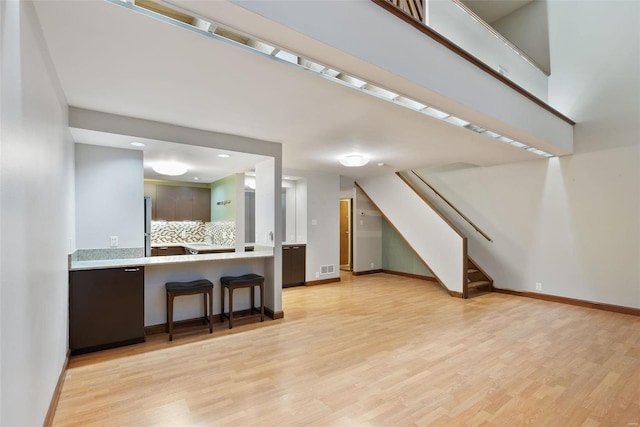 1052 S Kingshighway Blvd, Saint Louis, MO 63110 - unfurnished living room with stairs, light wood-style floors, and baseboards