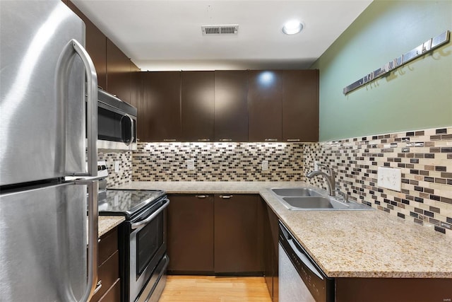 1052 S Kingshighway Blvd, Saint Louis, MO 63110 - kitchen with appliances with stainless steel finishes, a sink, dark brown cabinets, and tasteful backsplash