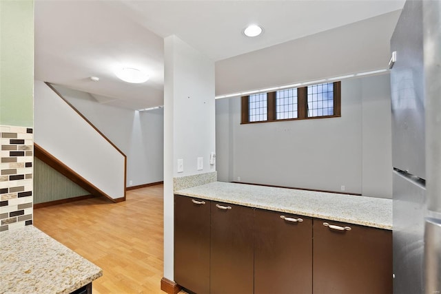 1052 S Kingshighway Blvd, Saint Louis, MO 63110 - bar area with freestanding refrigerator, light wood-style floors, stairway, and baseboards
