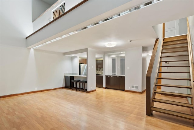 1052 S Kingshighway Blvd, Saint Louis, MO 63110 - unfurnished living room featuring stairway, light wood-type flooring, and baseboards