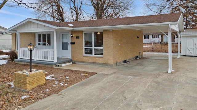 ranch-style house featuring concrete driveway, brick siding, a porch, a carport, and a shingled roof