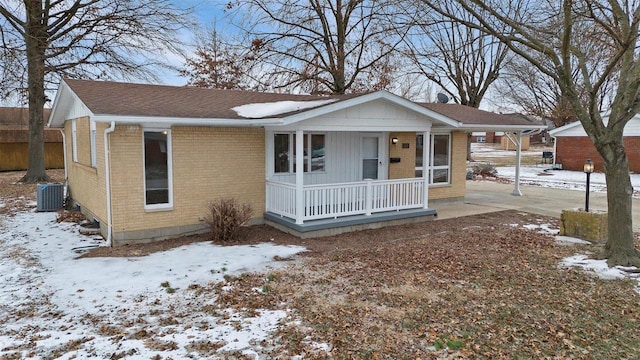 view of front of house with covered porch, brick siding, central air condition unit, and a shingled roof