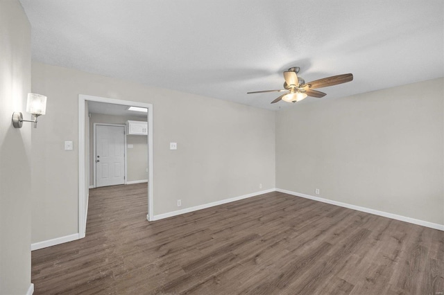 empty room with a ceiling fan, dark wood-type flooring, and baseboards