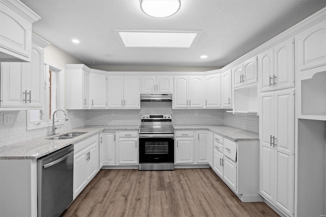 kitchen featuring stainless steel appliances, a sink, wood finished floors, backsplash, and recessed lighting