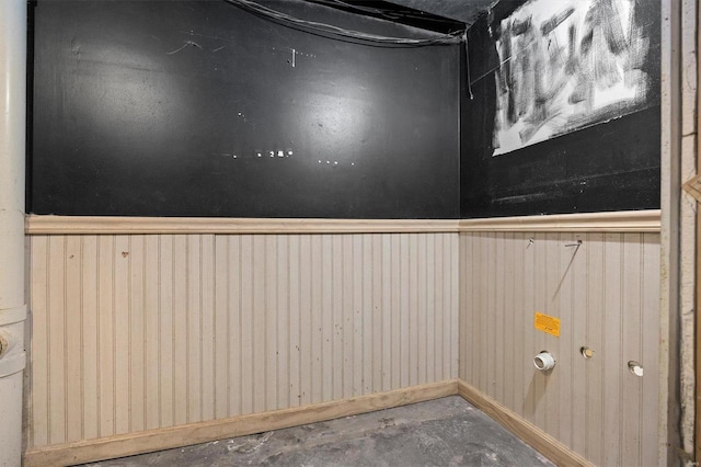 detailed view of unfinished concrete floors, wooden walls, and wainscoting