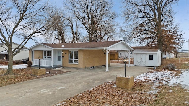 single story home with a storage shed, covered porch, driveway, an outdoor structure, and brick siding