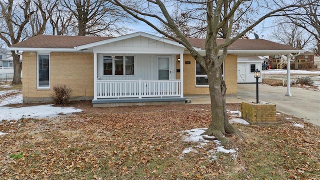 single story home featuring a porch, an attached carport, brick siding, and concrete driveway