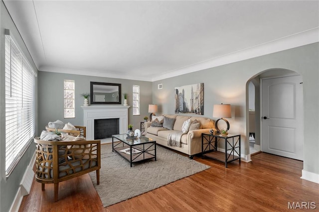 5807 Columbia Ave, Saint Louis, MO 63139 - living room with arched walkways, wood finished floors, a fireplace, baseboards, and crown molding