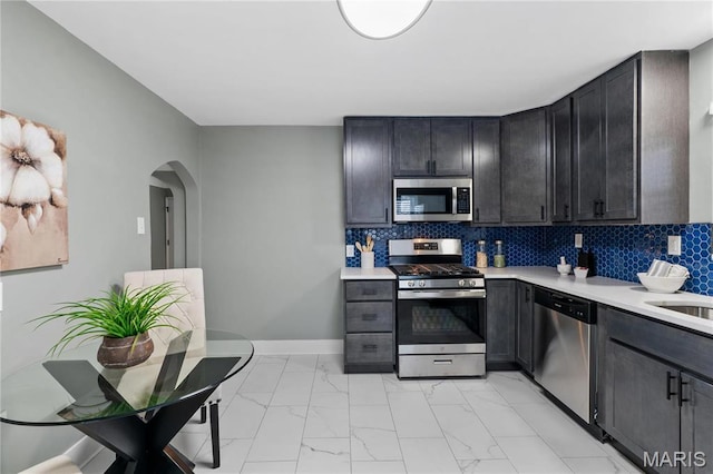 5807 Columbia Ave, Saint Louis, MO 63139 - kitchen featuring appliances with stainless steel finishes, light marble finish flooring, light countertops, and arched walkways