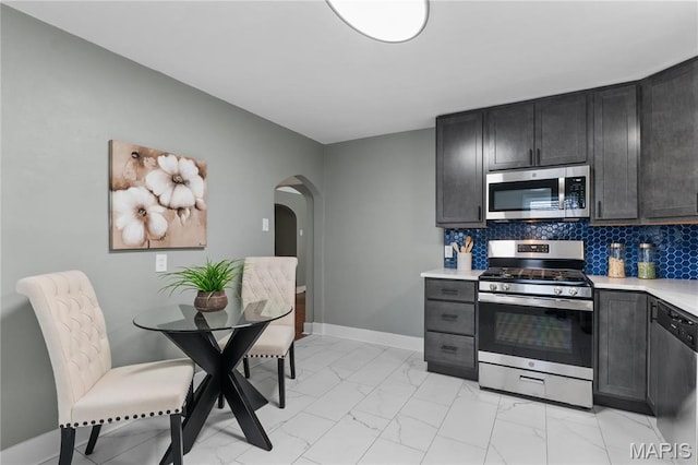 5807 Columbia Ave, Saint Louis, MO 63139 - kitchen with appliances with stainless steel finishes, arched walkways, light marble finish flooring, light countertops, and baseboards