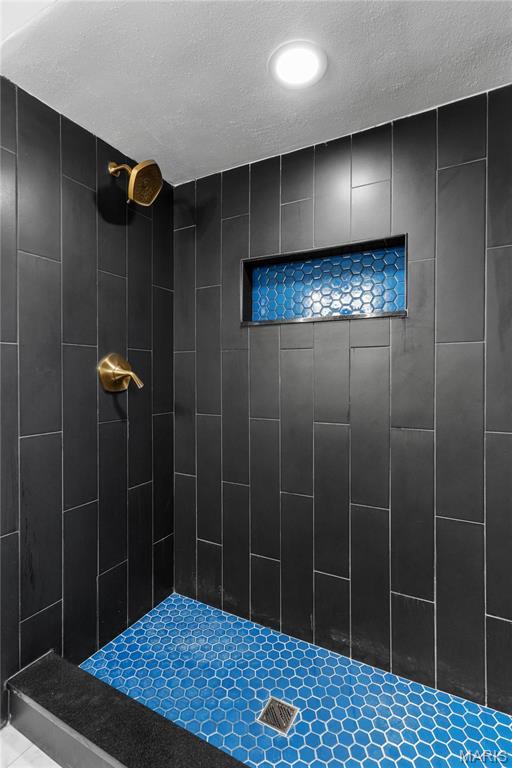 5807 Columbia Ave, Saint Louis, MO 63139 - bathroom featuring tiled shower and a textured ceiling