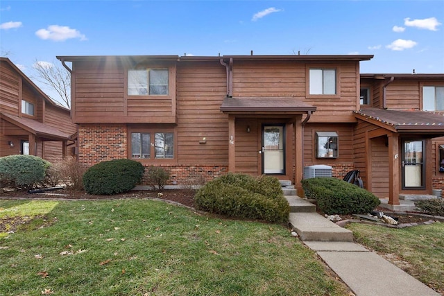 townhome / multi-family property featuring a front yard, brick siding, and central AC
