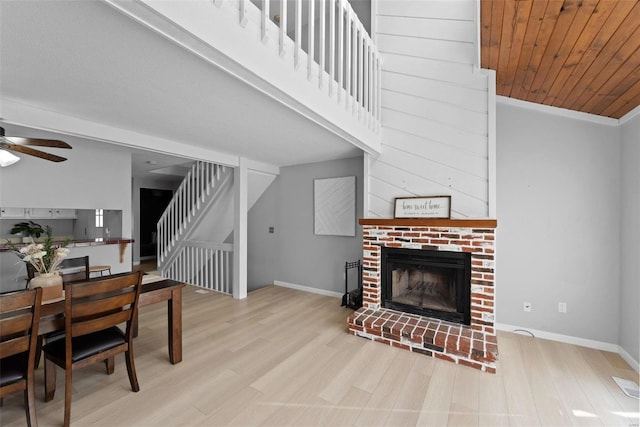 living room with a ceiling fan, stairway, wood finished floors, a fireplace, and baseboards