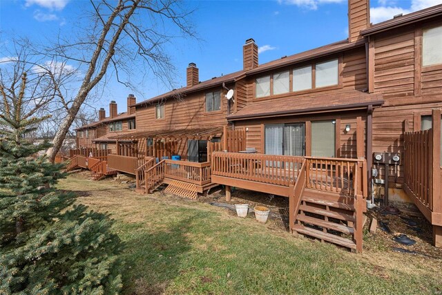 rear view of house with a chimney, a yard, a deck, and stairs