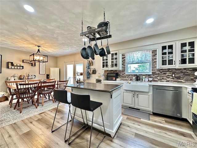6 Ravenwood Cir, Ofallon, IL 62269 - kitchen featuring stainless steel dishwasher, a sink, decorative backsplash, light wood-style floors, and glass insert cabinets