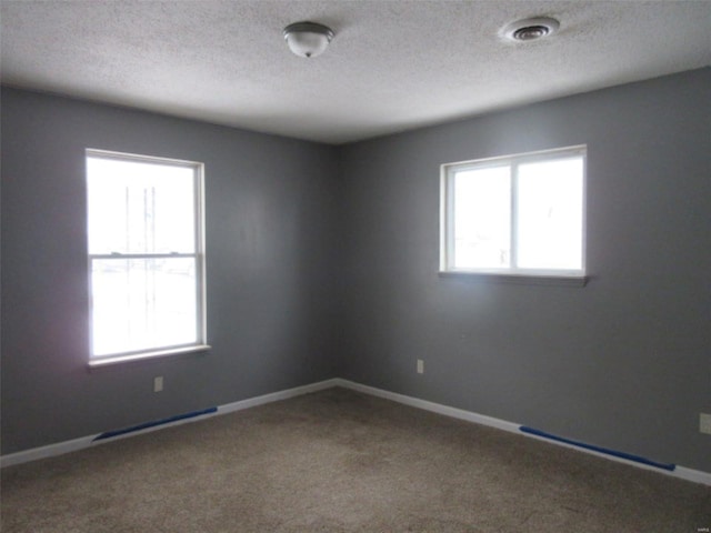 carpeted spare room with a textured ceiling and baseboards