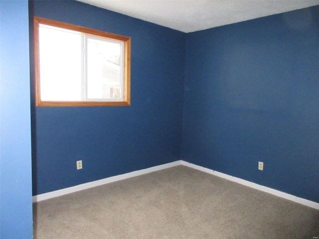 carpeted spare room featuring baseboards