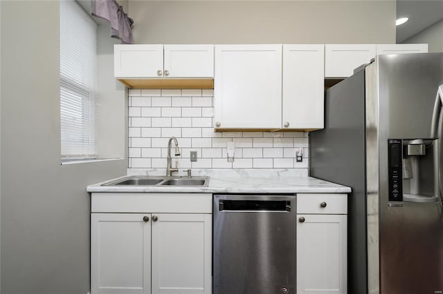 7915 S Broadway, Saint Louis, MO 63111 - kitchen featuring appliances with stainless steel finishes, a sink, decorative backsplash, white cabinets, and light stone countertops