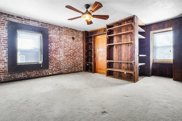 1317 Shenandoah Ave, Saint Louis, MO 63104 - unfurnished living room with brick wall, wood walls, carpet, a ceiling fan, and a textured ceiling