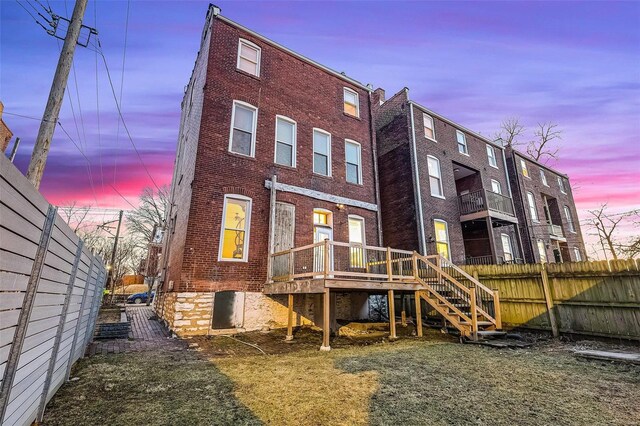 1317 Shenandoah Ave, Saint Louis, MO 63104 - back of house at dusk with brick siding, fence, stairs, and a deck