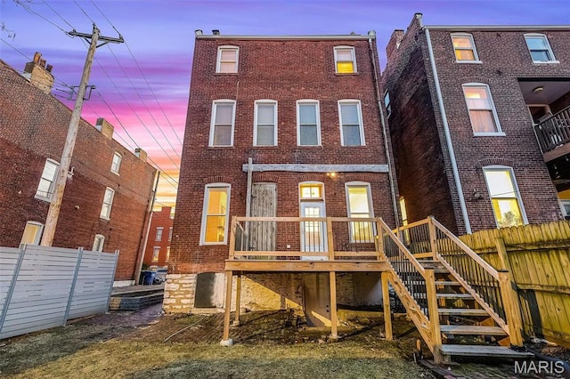 1317 Shenandoah Ave, Saint Louis, MO 63104 - back of house at dusk with brick siding, a deck, and stairs