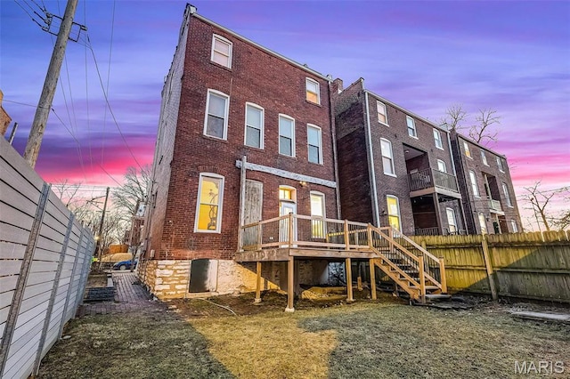 1317 Shenandoah Ave, Saint Louis, MO 63104 - back of house at dusk with brick siding, a wooden deck, and stairs