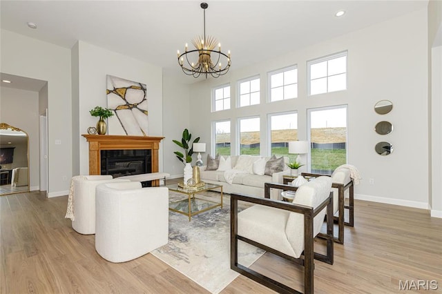 212 Terradel Trl, Foristell, MO 63348 - living room featuring light wood-style flooring, a glass covered fireplace, a chandelier, baseboards, and recessed lighting
