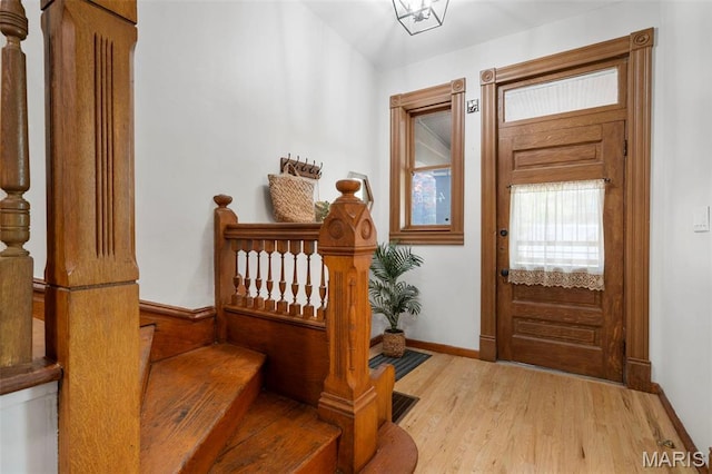 foyer with light wood-style floors, baseboards, and stairs
