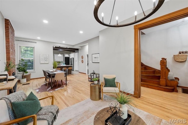 living room featuring light wood-type flooring, recessed lighting, baseboards, stairs, and a chandelier
