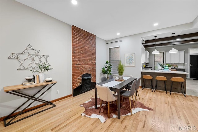 dining space featuring recessed lighting, light wood-type flooring, a brick fireplace, and baseboards