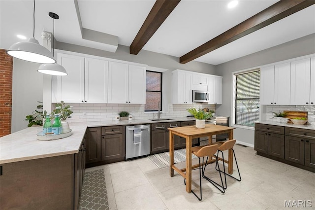 kitchen featuring stainless steel appliances, decorative backsplash, a sink, white cabinetry, and beamed ceiling