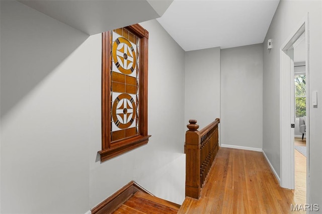 corridor with an upstairs landing, light wood-style flooring, and baseboards