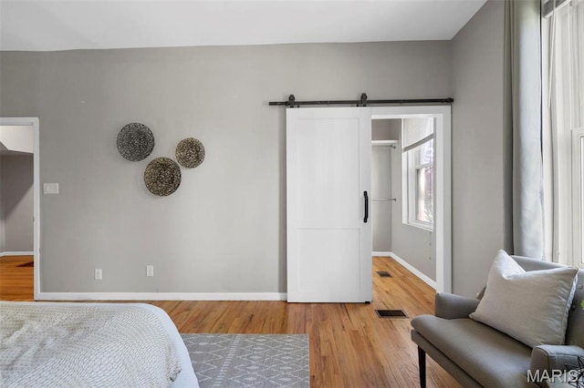 bedroom featuring light wood finished floors, baseboards, and a barn door
