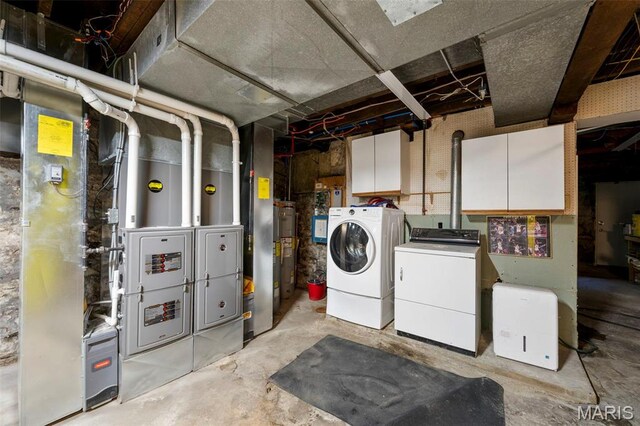 clothes washing area with cabinet space, separate washer and dryer, and water heater