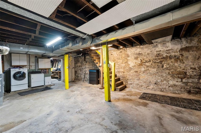 unfinished below grade area featuring washing machine and clothes dryer and stairs