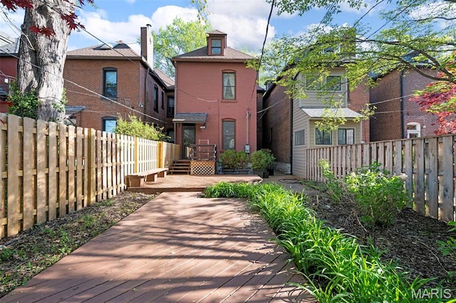 back of house featuring a deck, a fenced backyard, and brick siding
