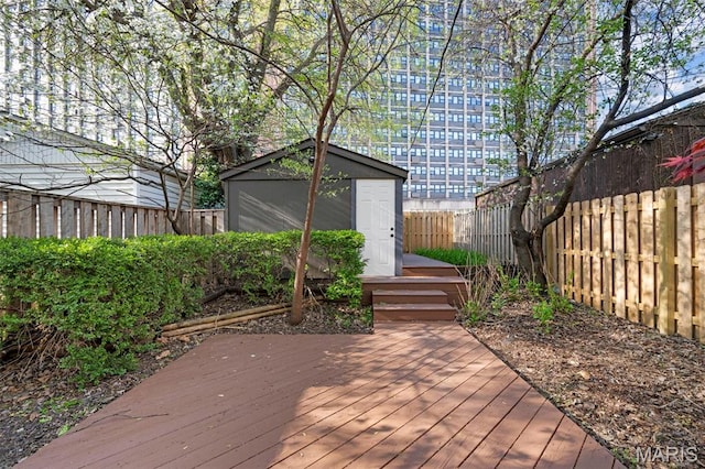 wooden terrace with a fenced backyard, an outbuilding, and a storage unit