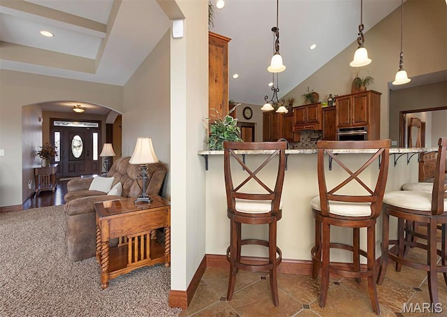 9606 Klings Ct, Mascoutah, IL 62258 - kitchen with arched walkways, brown cabinets, a breakfast bar, baseboards, and pendant lighting