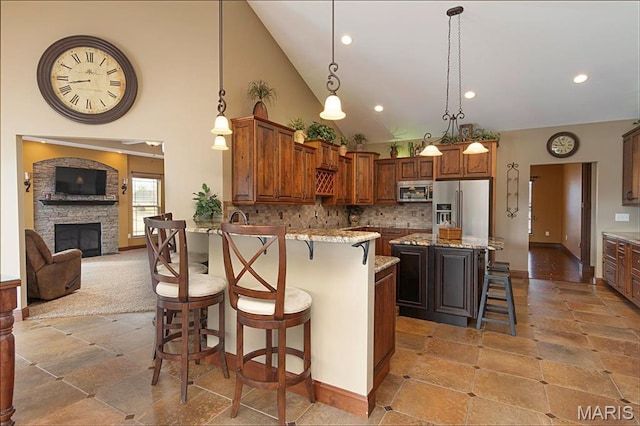 9606 Klings Ct, Mascoutah, IL 62258 - kitchen featuring stainless steel appliances, a breakfast bar, light stone countertops, high vaulted ceiling, and stone tile floors