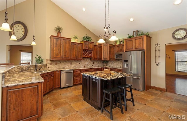 9606 Klings Ct, Mascoutah, IL 62258 - kitchen with stainless steel appliances, stone tile flooring, light stone counters, a sink, and a breakfast bar area