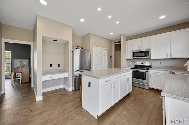 1218 Cold Spring Dr, Ofallon, MO 63368 - kitchen featuring stainless steel appliances, wood finished floors, a sink, a kitchen island, and light countertops