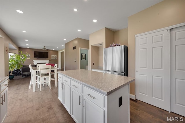 1218 Cold Spring Dr, Ofallon, MO 63368 - kitchen featuring freestanding refrigerator, a center island, recessed lighting, wood finished floors, and white cabinetry