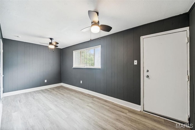 4649 Louisiana Ave, Saint Louis, MO 63111 - spare room featuring a ceiling fan, light wood-style floors, baseboards, and wooden walls