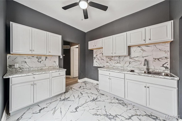 4649 Louisiana Ave, Saint Louis, MO 63111 - kitchen with a sink, light marble finish flooring, ceiling fan, baseboards, and white cabinetry