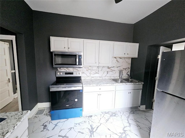 4649 Louisiana Ave, Saint Louis, MO 63111 - kitchen featuring appliances with stainless steel finishes, a sink, white cabinets, light marble finish flooring, and baseboards