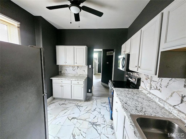 4649 Louisiana Ave, Saint Louis, MO 63111 - kitchen featuring appliances with stainless steel finishes, a ceiling fan, light marble finish floors, decorative backsplash, and white cabinetry